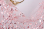 a close-up view of a delicate, pink, and white floral-patterned fabric, possibly a sheer or sheer lace material. The fabric appears to be made of sheer material, with a delicate and intricate design of leaves and flowers. The image does not contain any text or other discernible objects, and the focus is solely on the fabric's texture and pattern.
