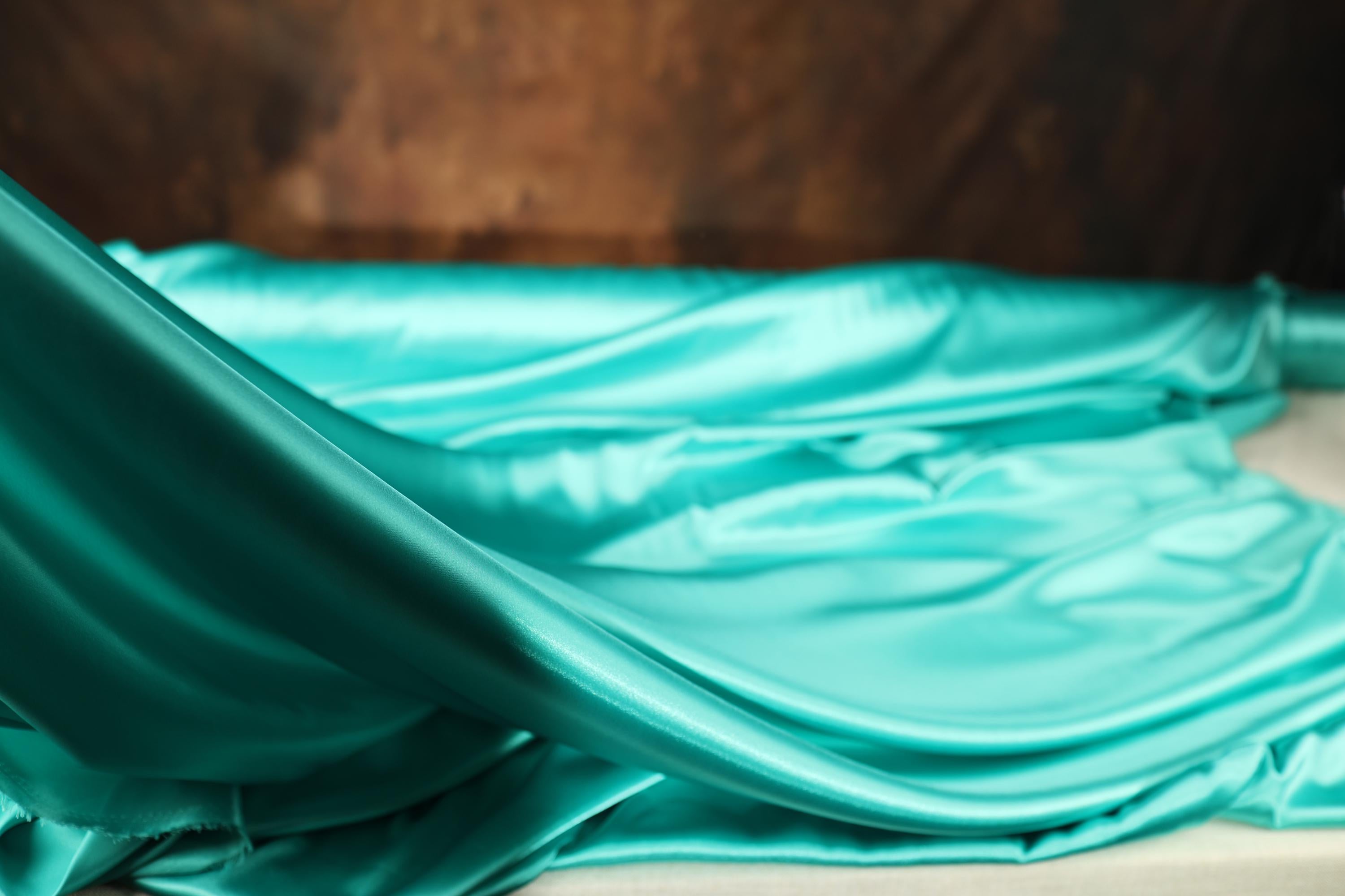 a bed with a blue sheet and a glass of wine