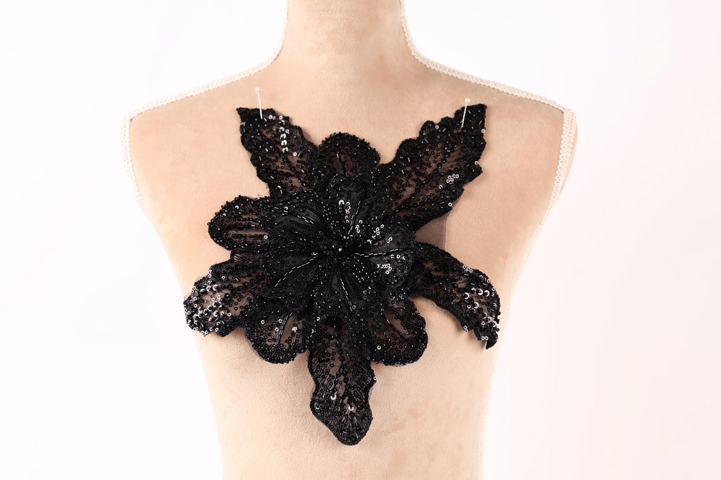 A mannequin wearing a dress with a large black sequined flower on the back.