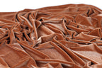 a close-up view of a crumpled, orange-brown fabric, possibly velvet, with a textured and wrinkled appearance.