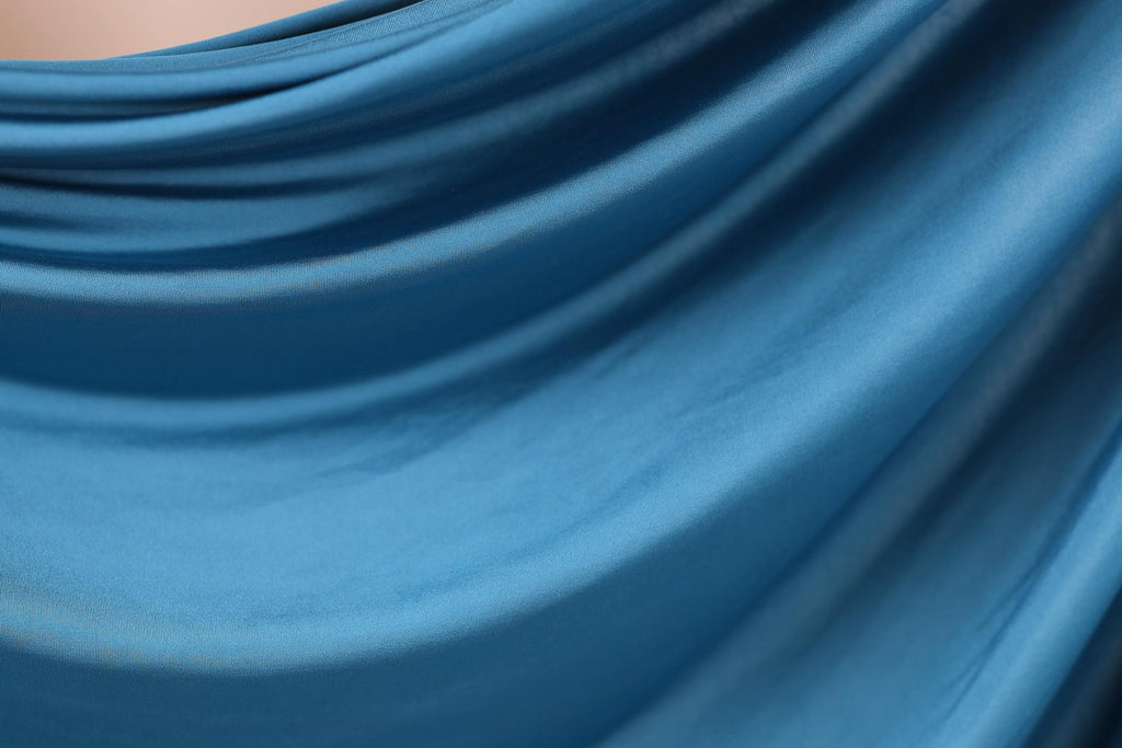 The image is a close-up of a blue fabric, possibly a piece of clothing or a textile. The fabric appears to be soft and smooth, with a slight texture that suggests it might be made of silk or a similar material. The image does not contain any discernible objects or actions, and there are no specific details provided about the color or pattern of the fabric.