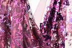 a close-up view of a fabric with a vibrant, multicolored pattern, including shades of pink, purple, and blue. The fabric appears to be made of sequins or other embellishments, adding a touch of sparkle and glamour to the design.