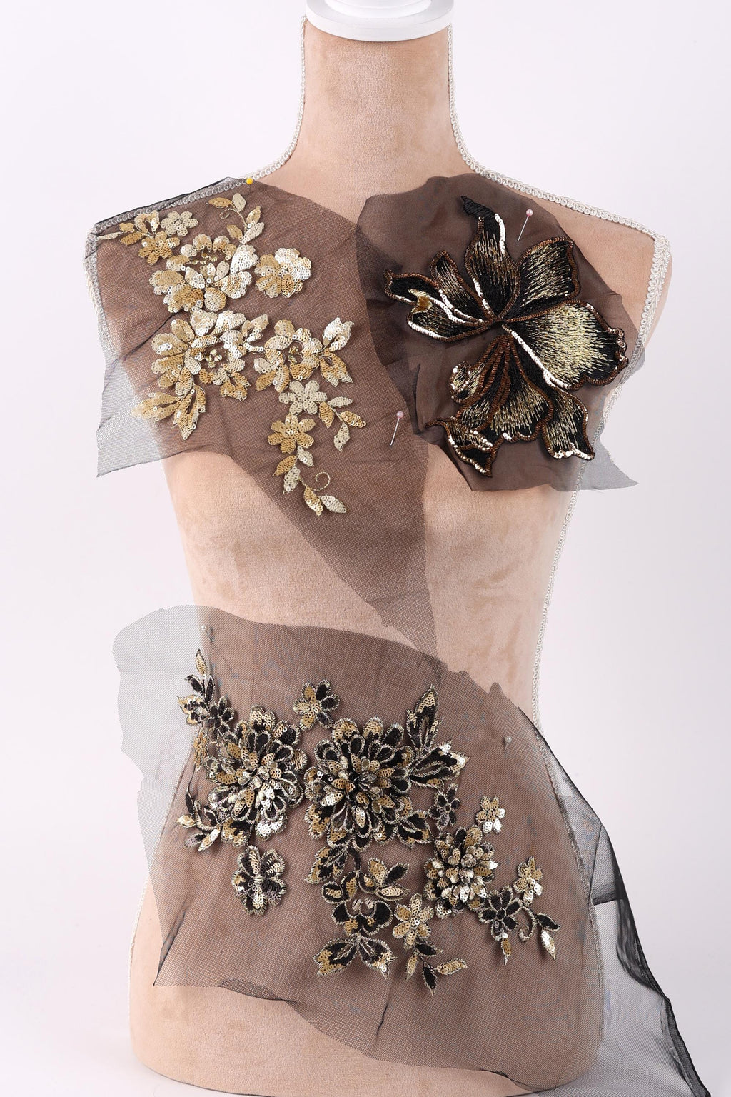 A mannequin wearing a dress with a floral pattern on the shoulder and a sheer, black fabric with a floral pattern on the lower body.