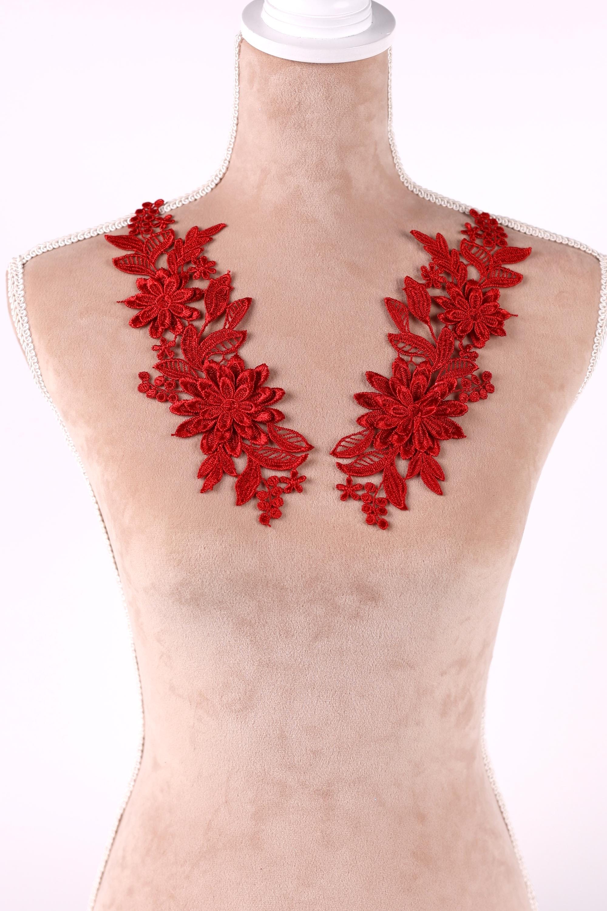 A mannequin wearing a red floral embroidered patch on the bust area.