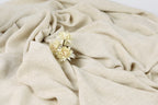 A close-up image of a beige fabric with delicate white flowers resting on it.