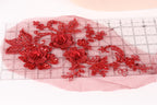 a close-up view of red floral embroidery on a transparent surface, with a ruler visible in the background.