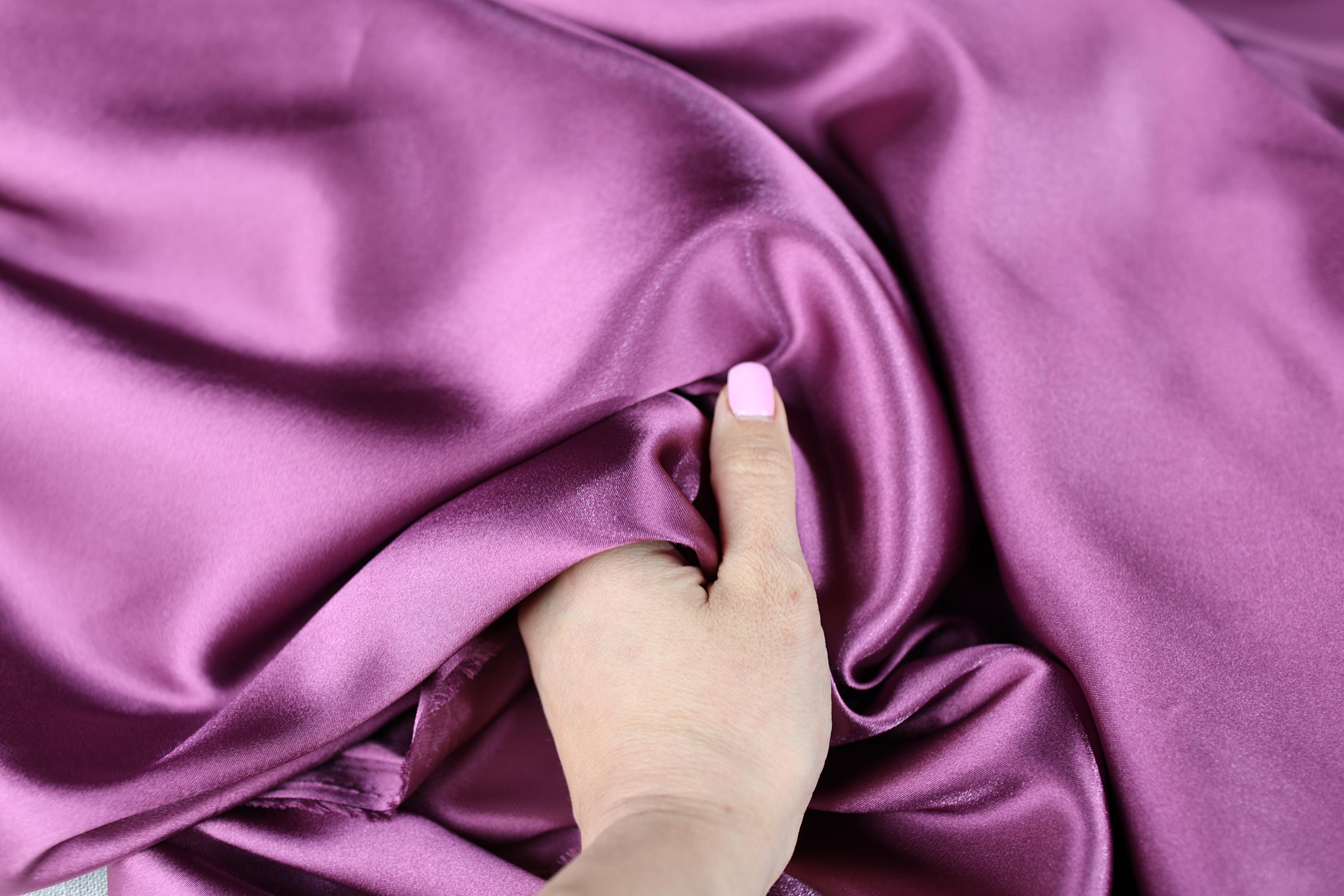 a woman&#39;s hand on a purple satin fabric
