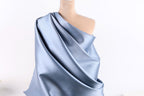 A mannequin wearing a blue satin fabric draped over its shoulder.