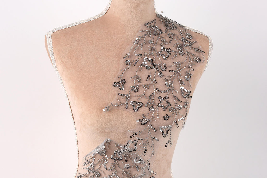 A mannequin torso with a decorative silver sequin patch on the shoulder.