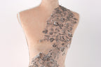 A mannequin torso with a decorative silver sequin patch on the shoulder.