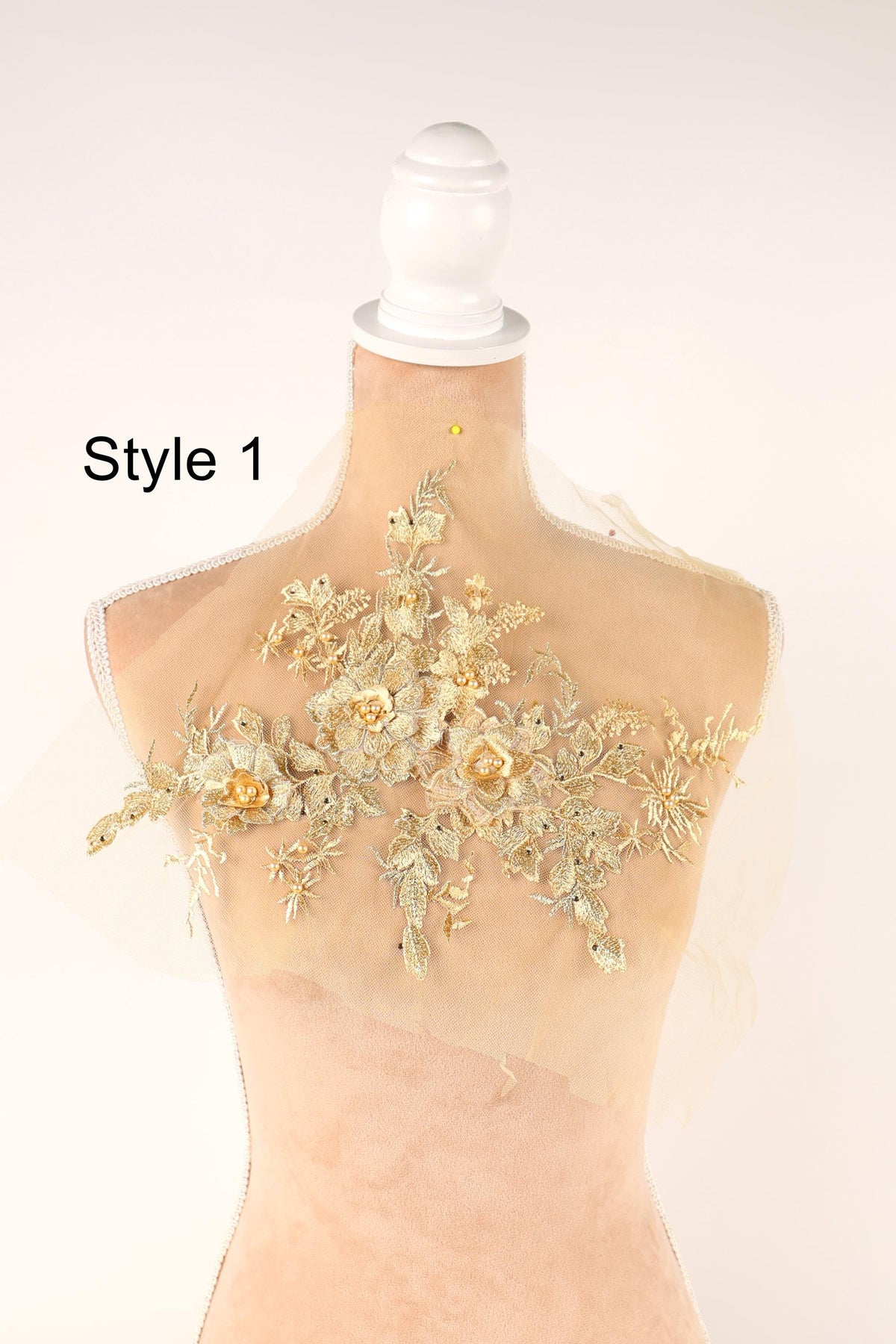 A mannequin with a decorative gold floral lace overlay on its bust.