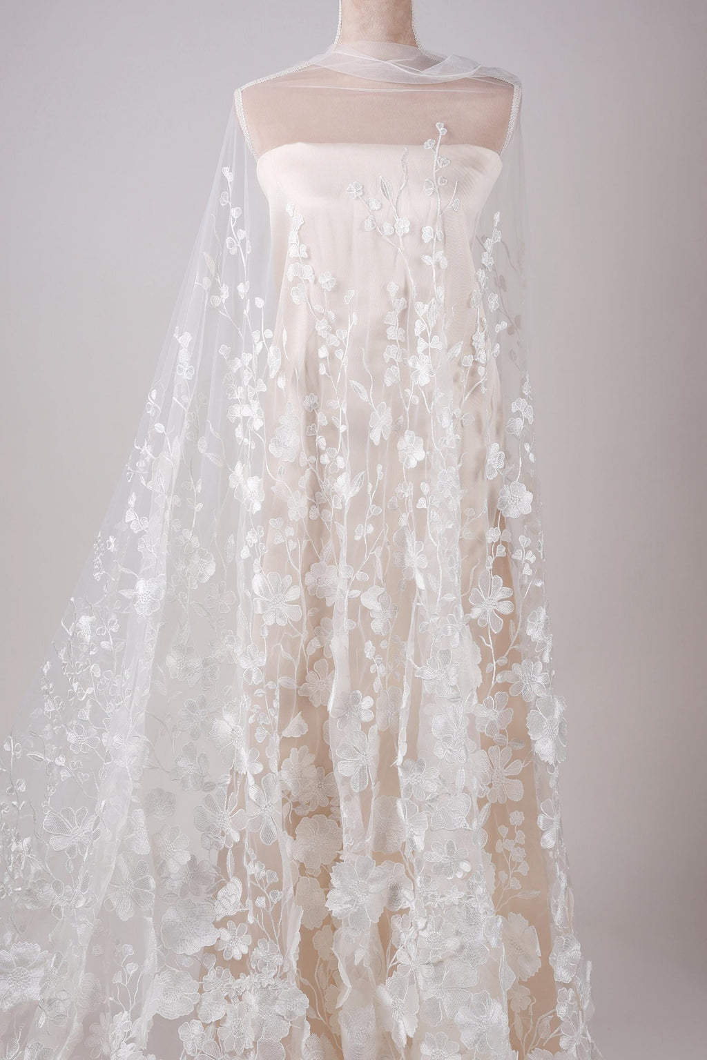 A white wedding dress with a long, flowing veil featuring delicate white floral embroidery.