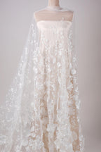 A white wedding dress with a long, flowing veil featuring delicate white floral embroidery.
