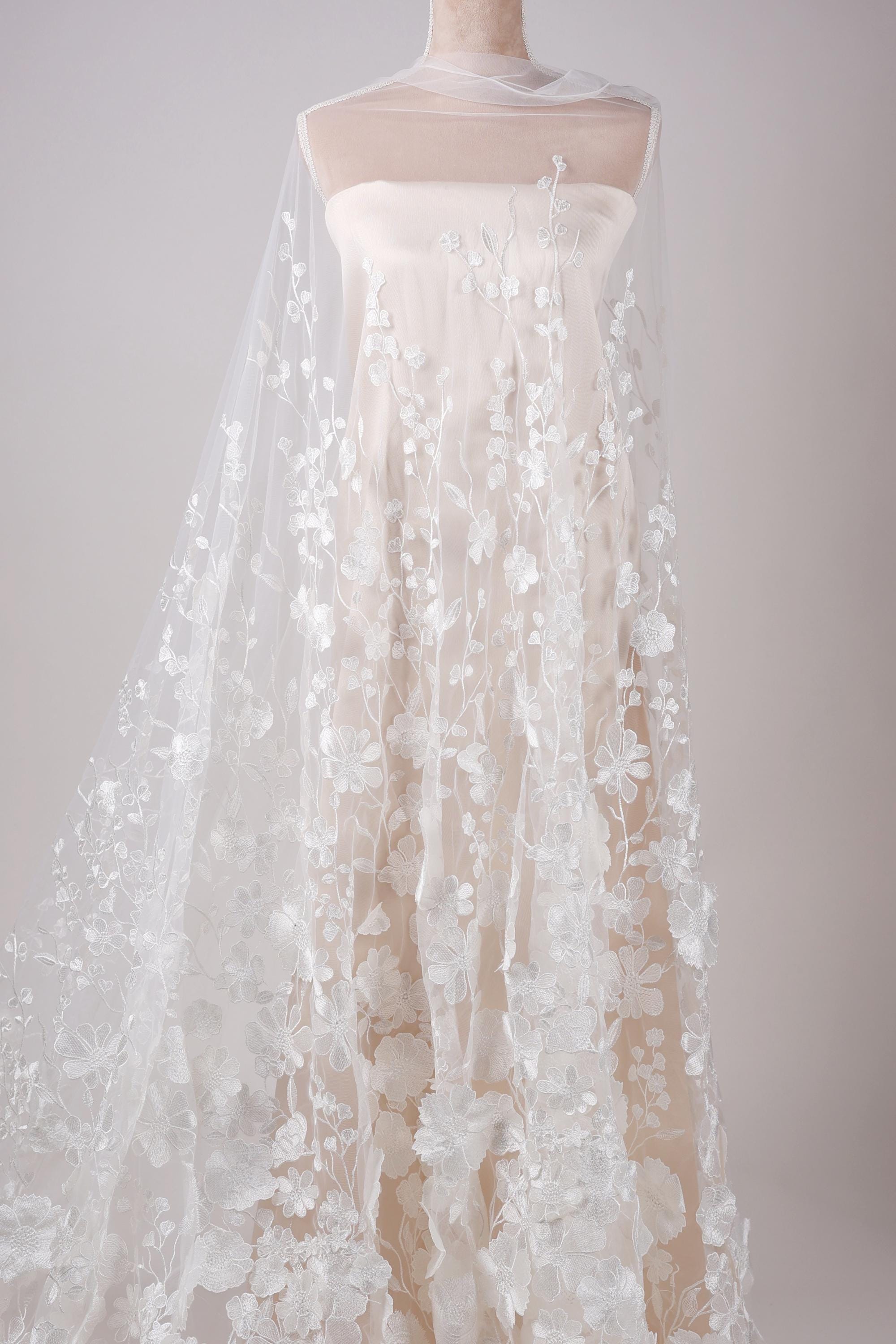 A white wedding dress with a long, flowing veil featuring delicate white floral embroidery.