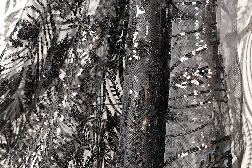 a close-up view of a black and grey sequined fabric, with intricate patterns and designs.
