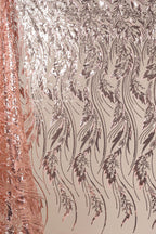 a close-up view of a fabric with a repeating pattern of pink and black sequin designs. The pattern consists of various shapes and lines, creating a visually striking and intricate design.