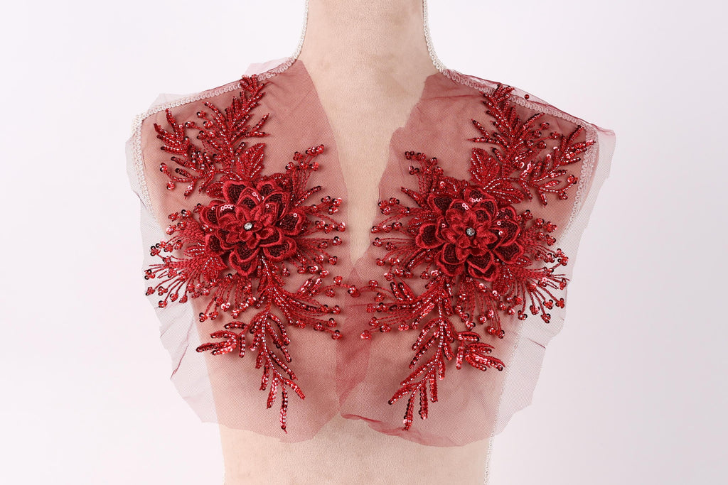 A mannequin wearing a red, sheer fabric with intricate floral embroidery.