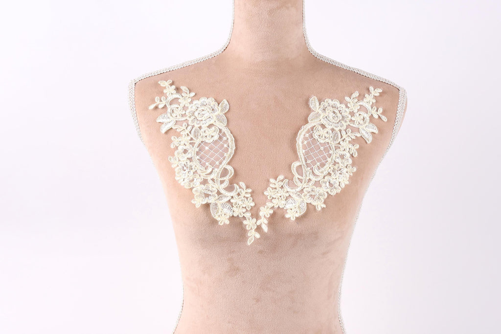 A mannequin with a white lace collar on its bust, featuring intricate floral and leaf designs.
