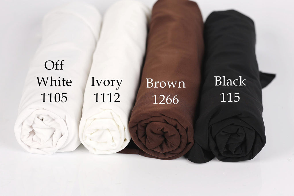 four rolled-up fabric swatches in different colors: white, ivory, brown, and black.