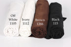 four rolled-up fabric swatches in different colors: white, ivory, brown, and black.