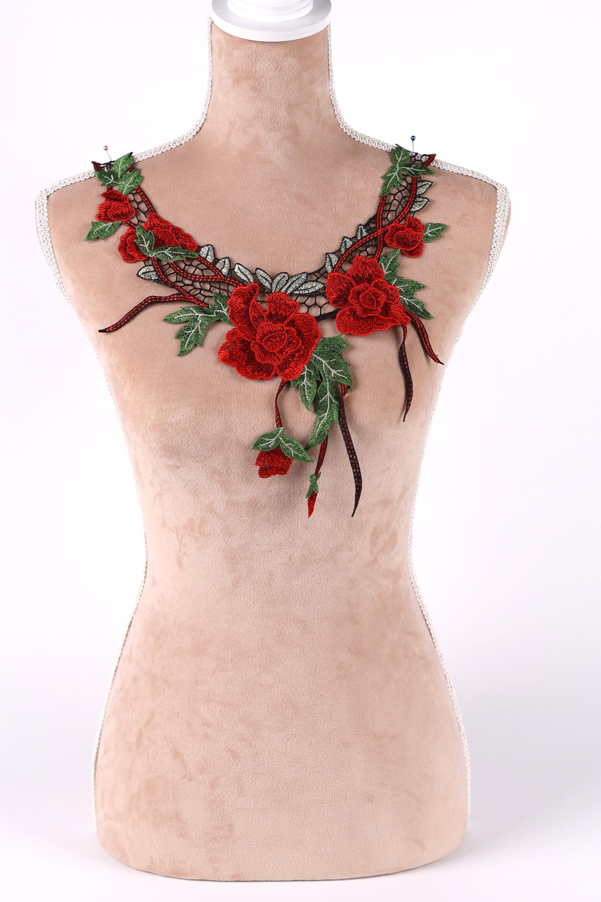 A mannequin wearing a necklace with red roses and green leaves.