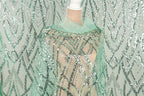 a mannequin wearing a green sequin dress with a sheer overlay. The dress has a pattern of green and silver sequins, creating a visually striking and intricate design.