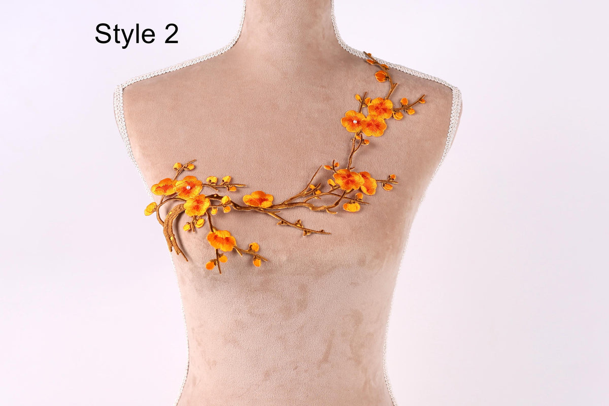 A mannequin with a floral embroidered design on its bust, featuring orange flowers and branches.