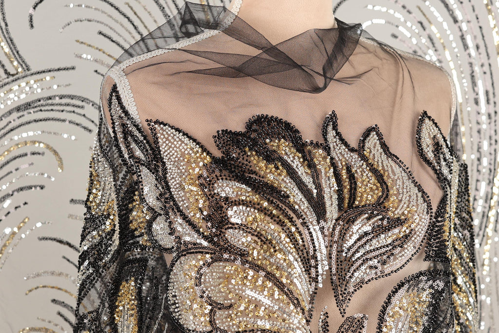 a mannequin wearing a dress with a sheer, sheer-like fabric and a floral pattern. The dress is adorned with sequins and beads, giving it a glamorous and elegant appearance.