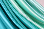 a close-up view of a fabric with a gradient of turquoise and mint colors, creating a visually appealing and textured appearance.