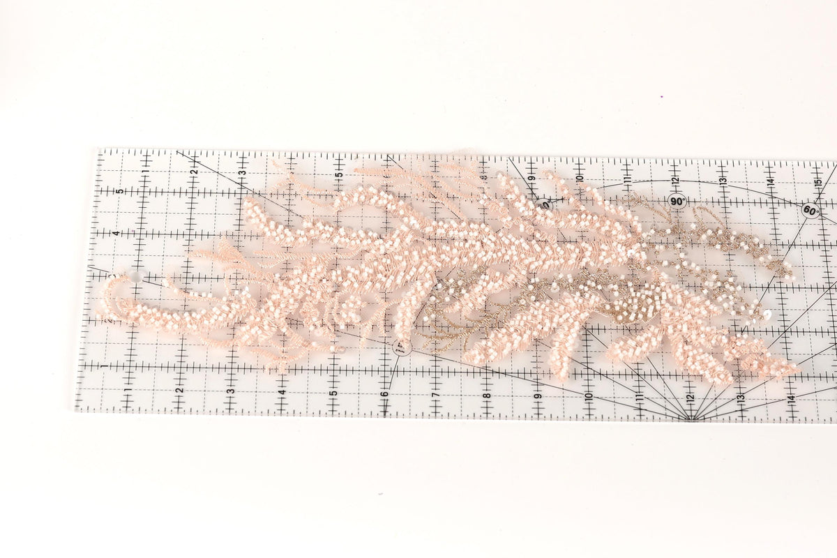 a clear ruler with a floral pattern of pink and beige beads on it.