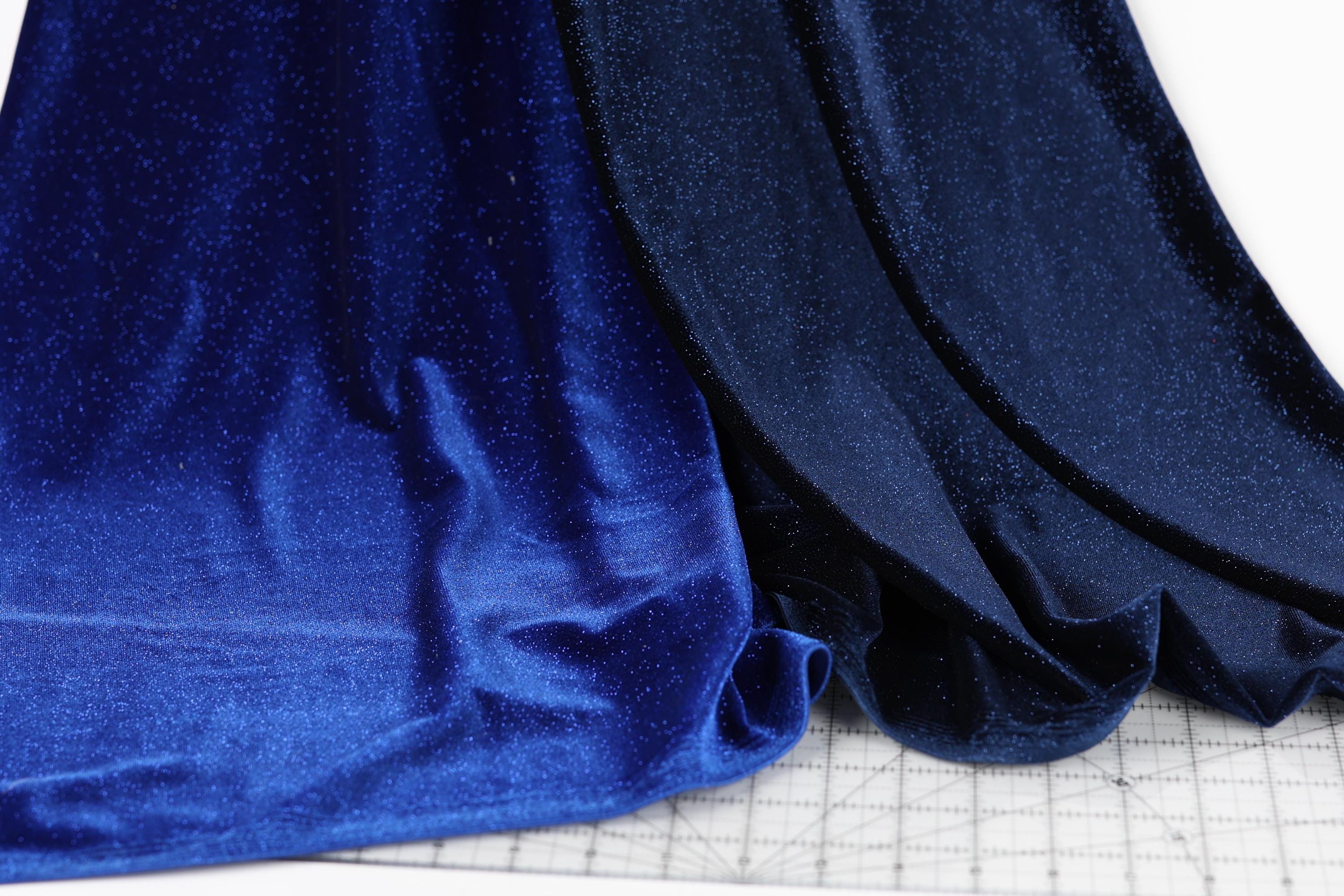 a close-up view of a blue fabric with a glittery texture, placed on a white surface.