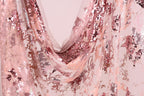a close-up view of a fabric with a pink and white sequined pattern. The fabric appears to be a sheer material, with a delicate and intricate design. The pattern consists of small sequins and beads that create a visually striking and eye-catching appearance. The fabric is draped in a way that it cascades down, creating a sense of movement and elegance.