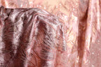 a close-up view of a fabric with a pink and gold sequined pattern, featuring a delicate and intricate design.
