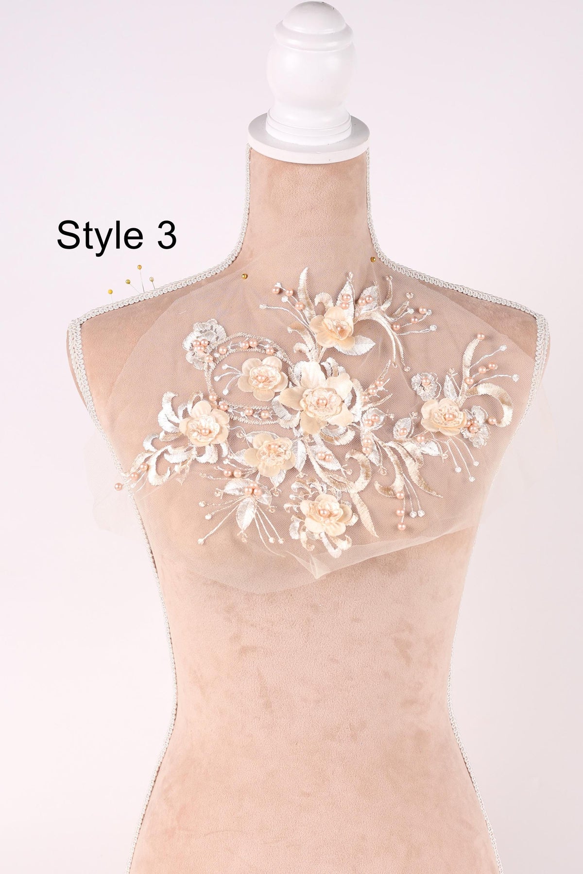 A mannequin with a decorative floral design on its bust, featuring delicate white flowers and leaves.