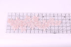 a clear ruler with a floral pattern of pink lace flowers placed on it.