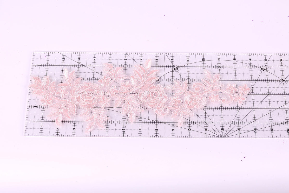 a clear ruler with a floral pattern of pink lace flowers placed on it.