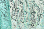 a close-up view of a fabric with a repeating pattern of green and black lines and shapes, creating a visually striking and intricate design.
