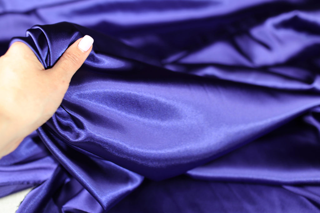 a woman&#39;s hand holding a purple cloth