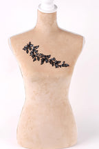 A mannequin with a beige body and a black leaf embroidered on its chest.