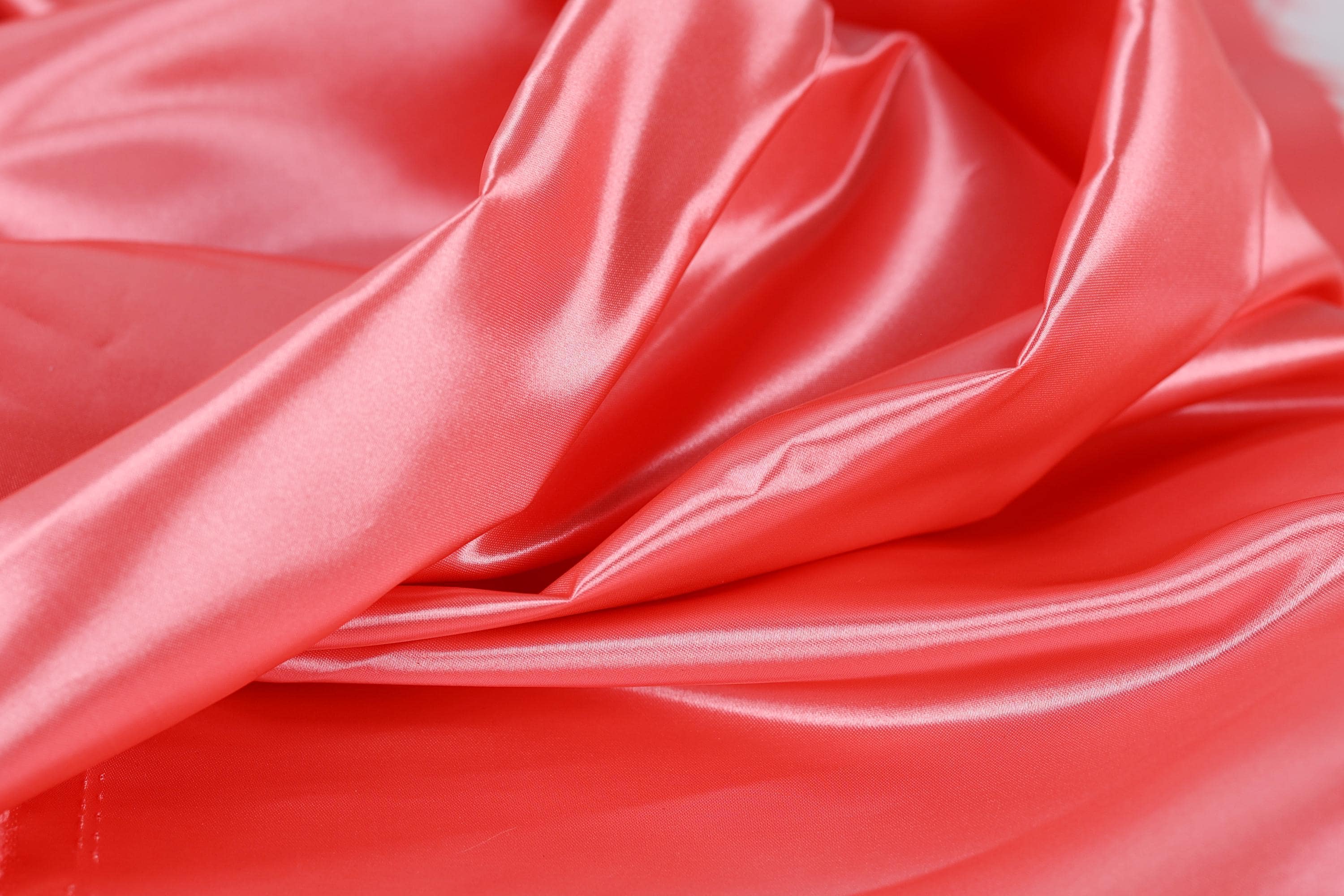 The image is a close-up of a shiny, smooth fabric with a bright red color.