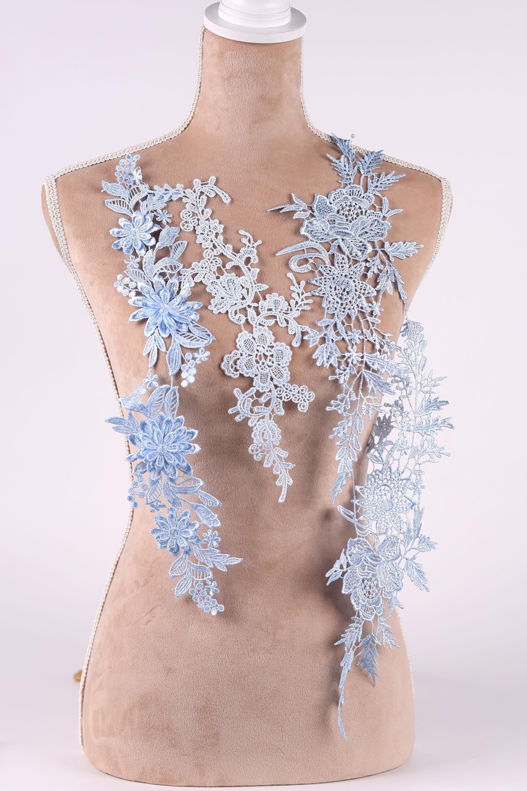A mannequin wearing a dress with blue floral lace appliques.
