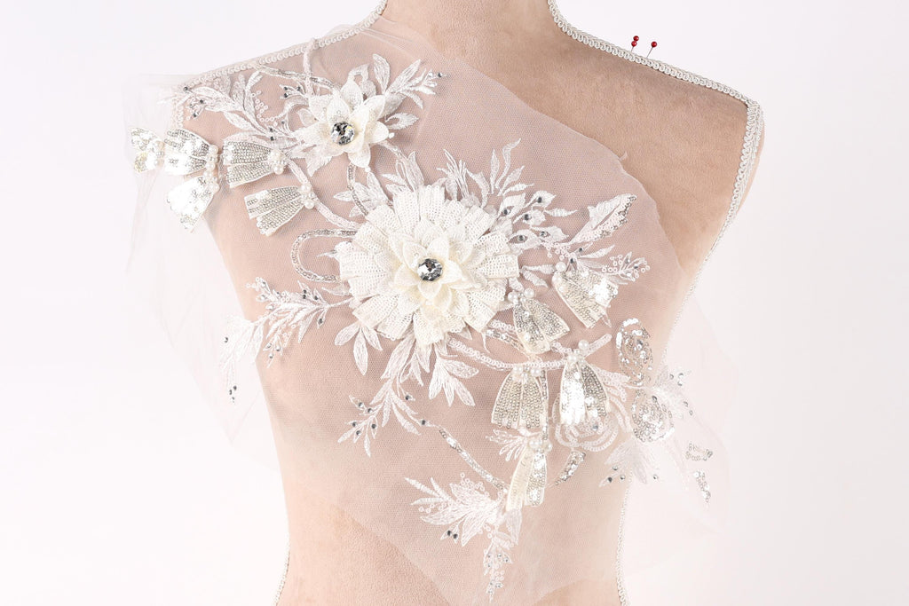 A mannequin wearing a white dress with intricate floral embroidery and sequins.