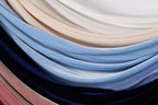 A close-up image of various colored velvet fabric swatches, including blue, pink, and white, arranged in a layered and textured manner.