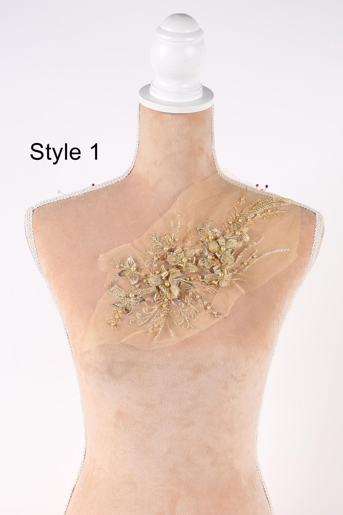 A mannequin with a decorative gold floral embellishment on its bust.