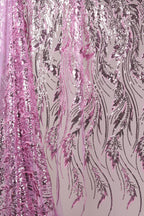 a close-up view of a fabric with a floral pattern in shades of pink and purple. The fabric appears to be sequined, with a repeating pattern of pink and purple lines and leaves. The fabric is hanging, creating a visually striking and intricate design.
