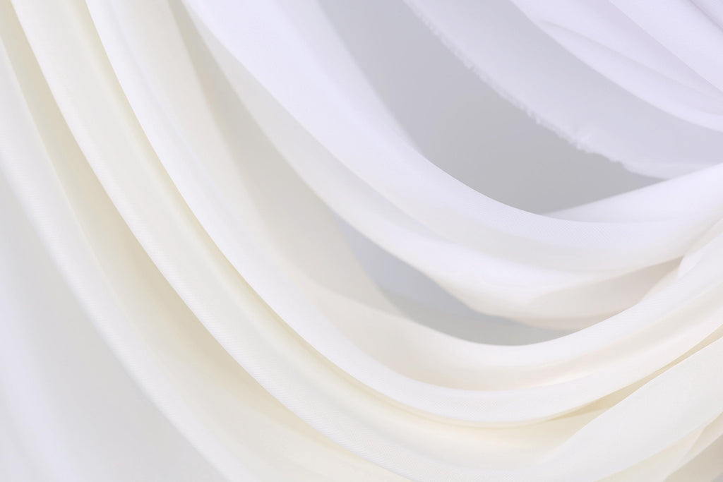 The image is a close-up of a white fabric, possibly a sheer or sheer-like material, with a soft, flowing texture.