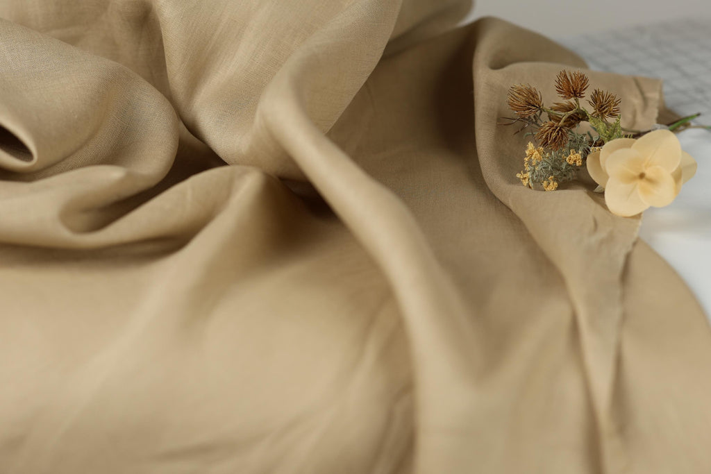 a close-up view of a beige fabric, with a small bouquet of flowers resting on it.