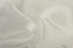 The image is a close-up of a soft, white fabric, possibly silk or chiffon, with a slightly wrinkled texture.