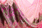 a close-up view of a fabric with a pink and green floral pattern. The fabric appears to be made of a shiny, sequined material, giving it a luxurious and eye-catching appearance.