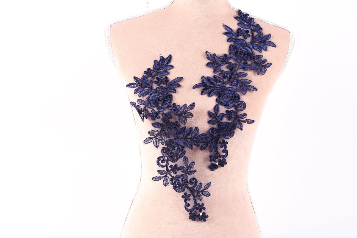 A mannequin torso with a decorative blue floral lace overlay.